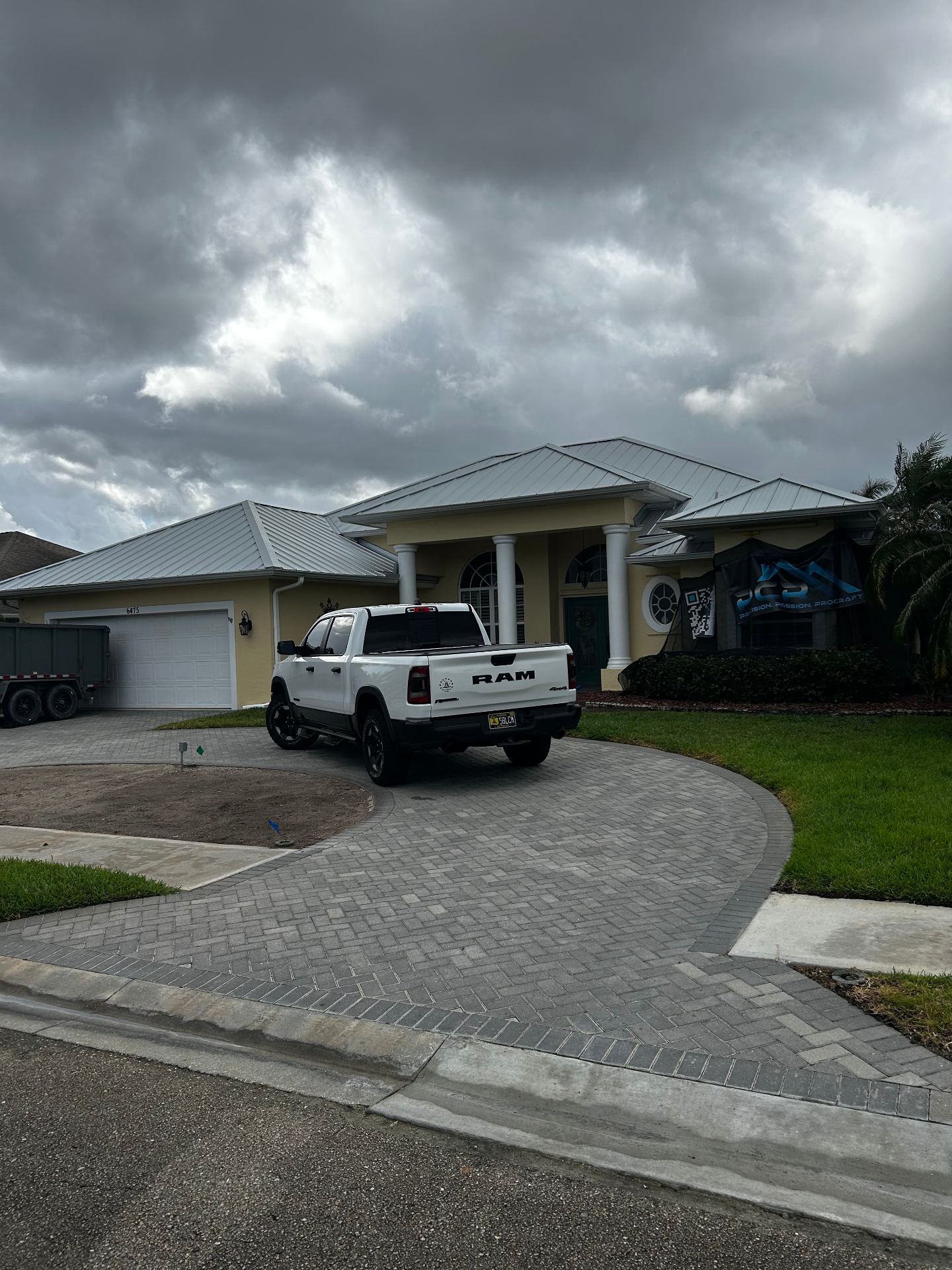 Silver standing-seam metal roof on a Florida home with ProCraft jobsite banner and dump trailer