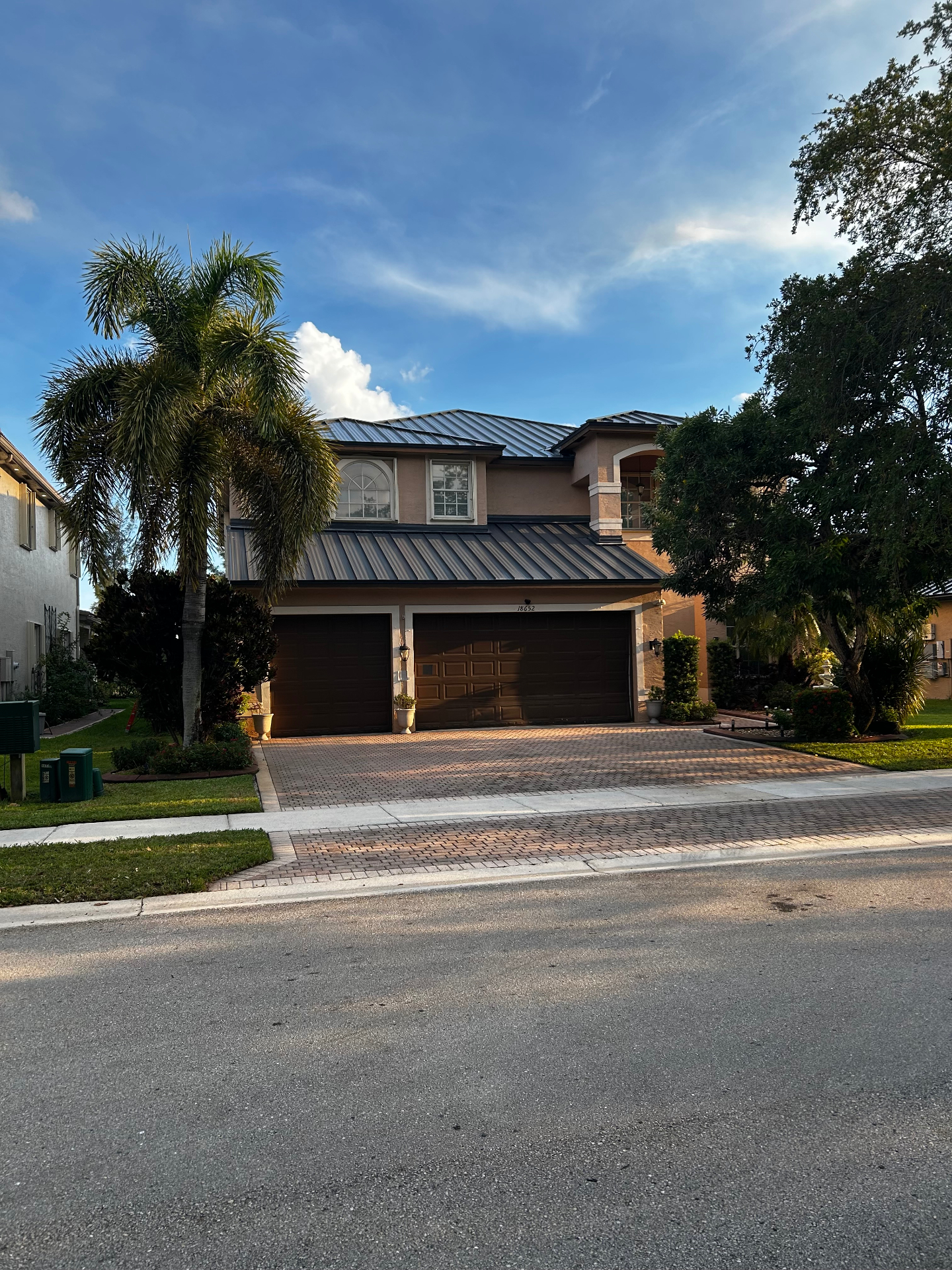 Two-story Florida home with a completed dark standing-seam metal roof and matching lower roof sections