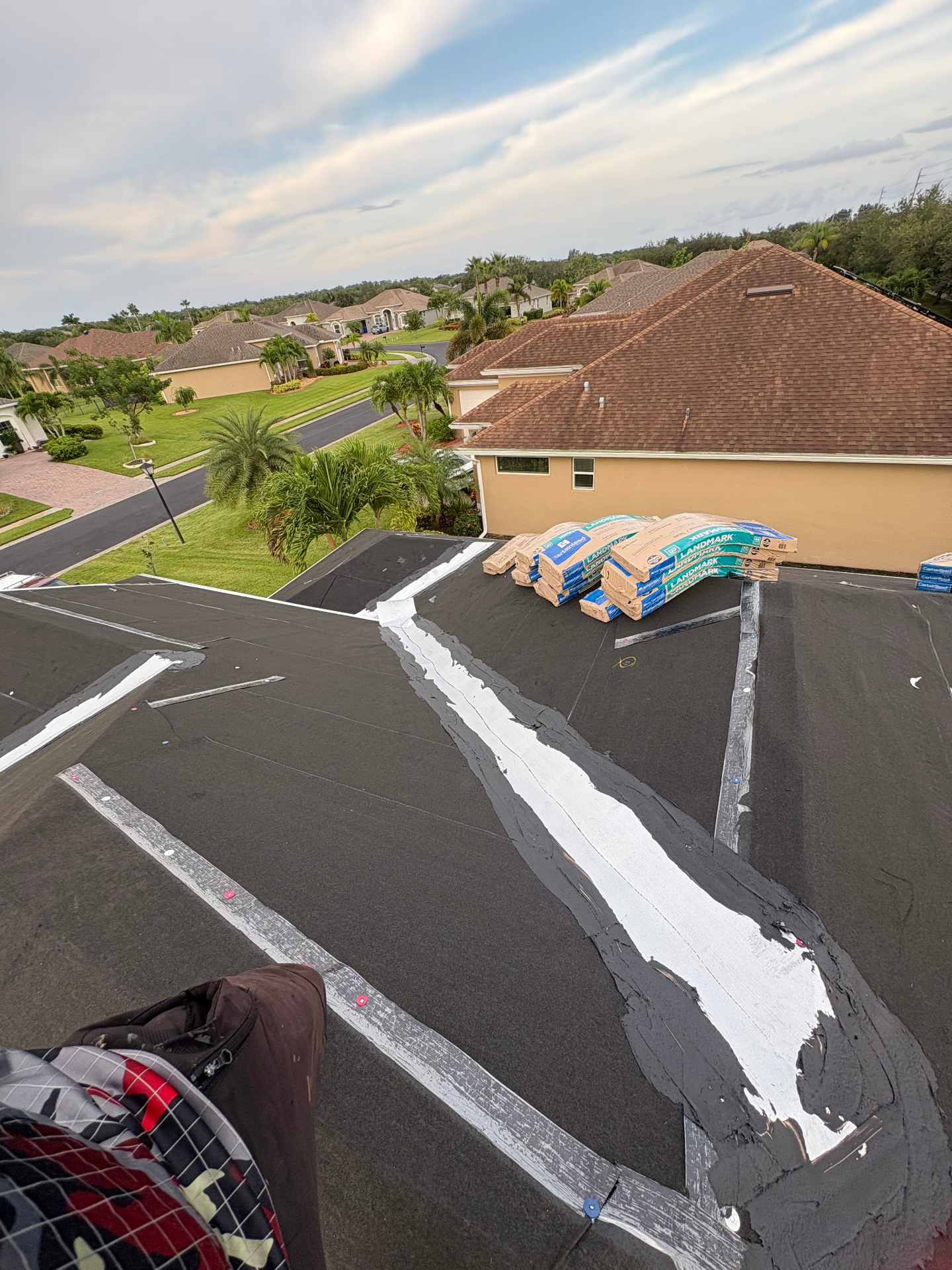 Modified bitumen flat roof repair with fresh seam sealant and CertainTeed Landmark shingle bundles staged on rooftop