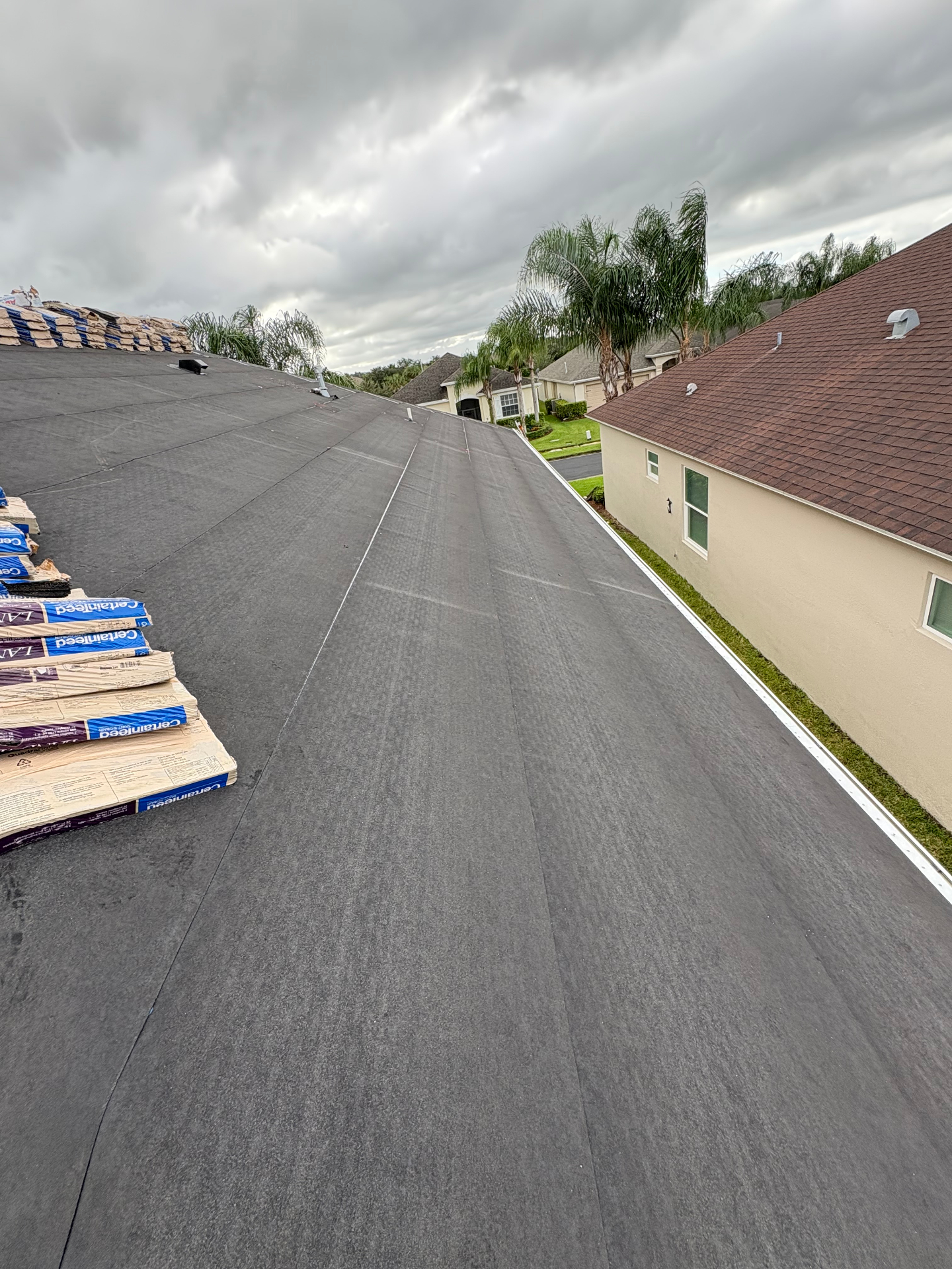 Shingle roof replacement in progress — underlayment installed with CertainTeed Landmark shingle bundles staged for installation
