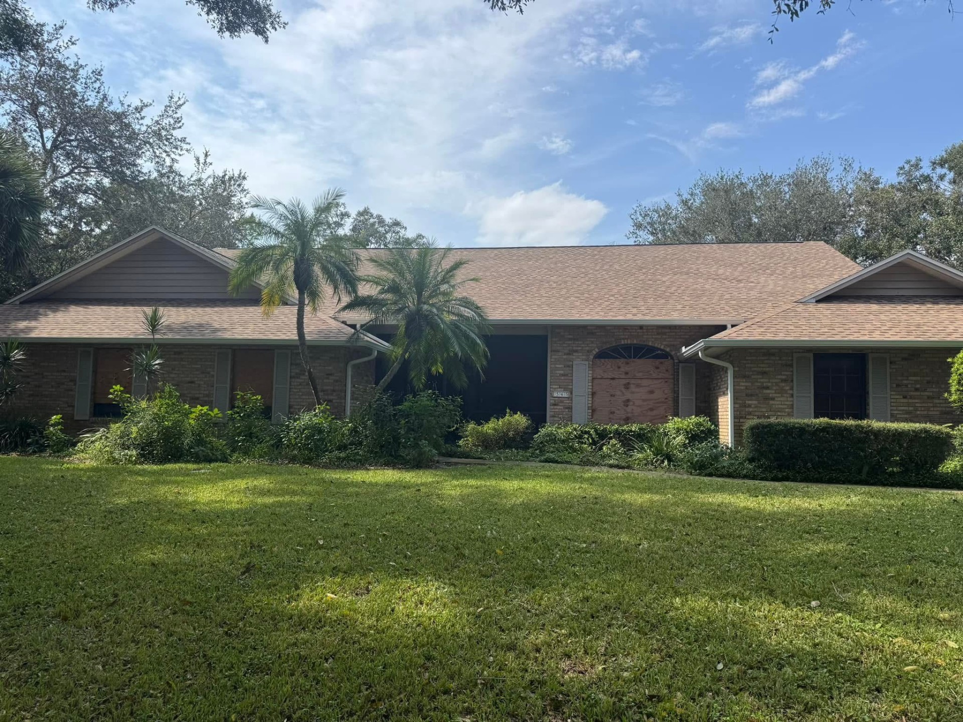 Completed warm-tone architectural shingle roof on a brick ranch home in Florida